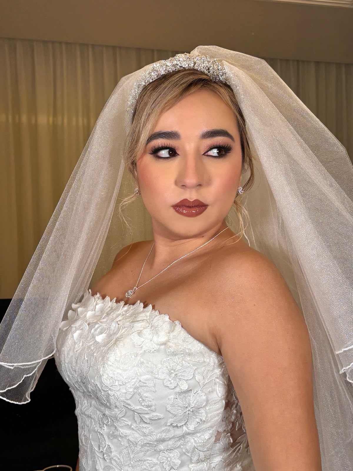 Novia con velo y tocado de cristales, recogido suelto y labial vino oscuro.