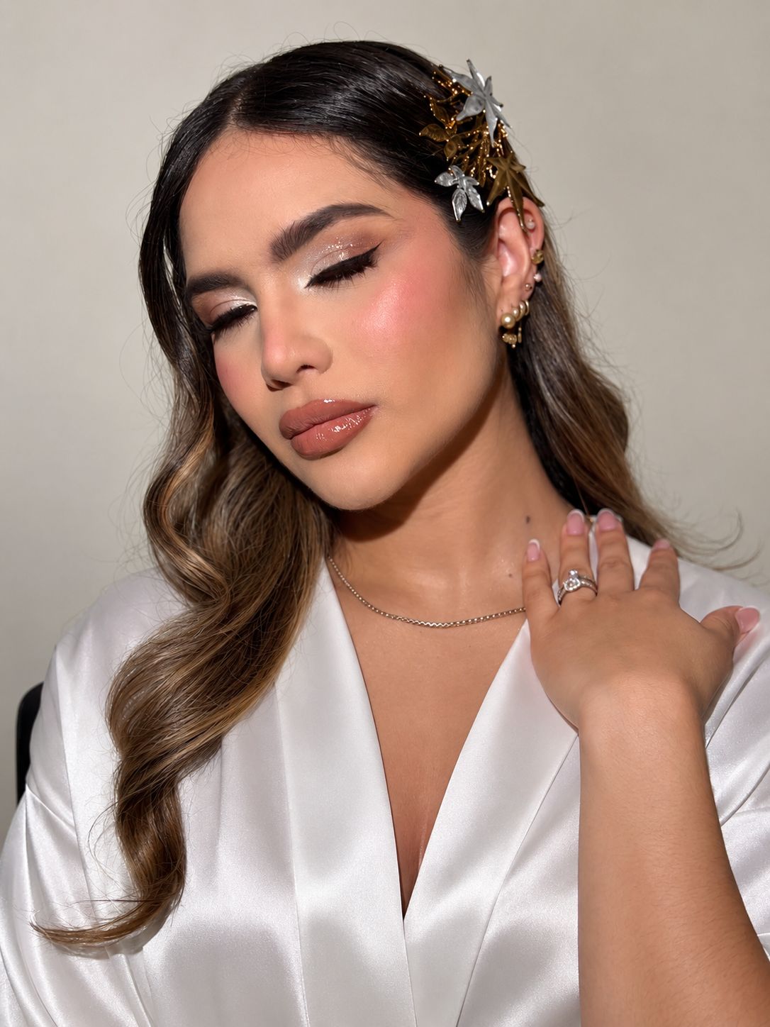 Novia con maquillaje natural luminoso, ondas suaves y tocado floral dorado, trabajo de Sandra Pámanes.